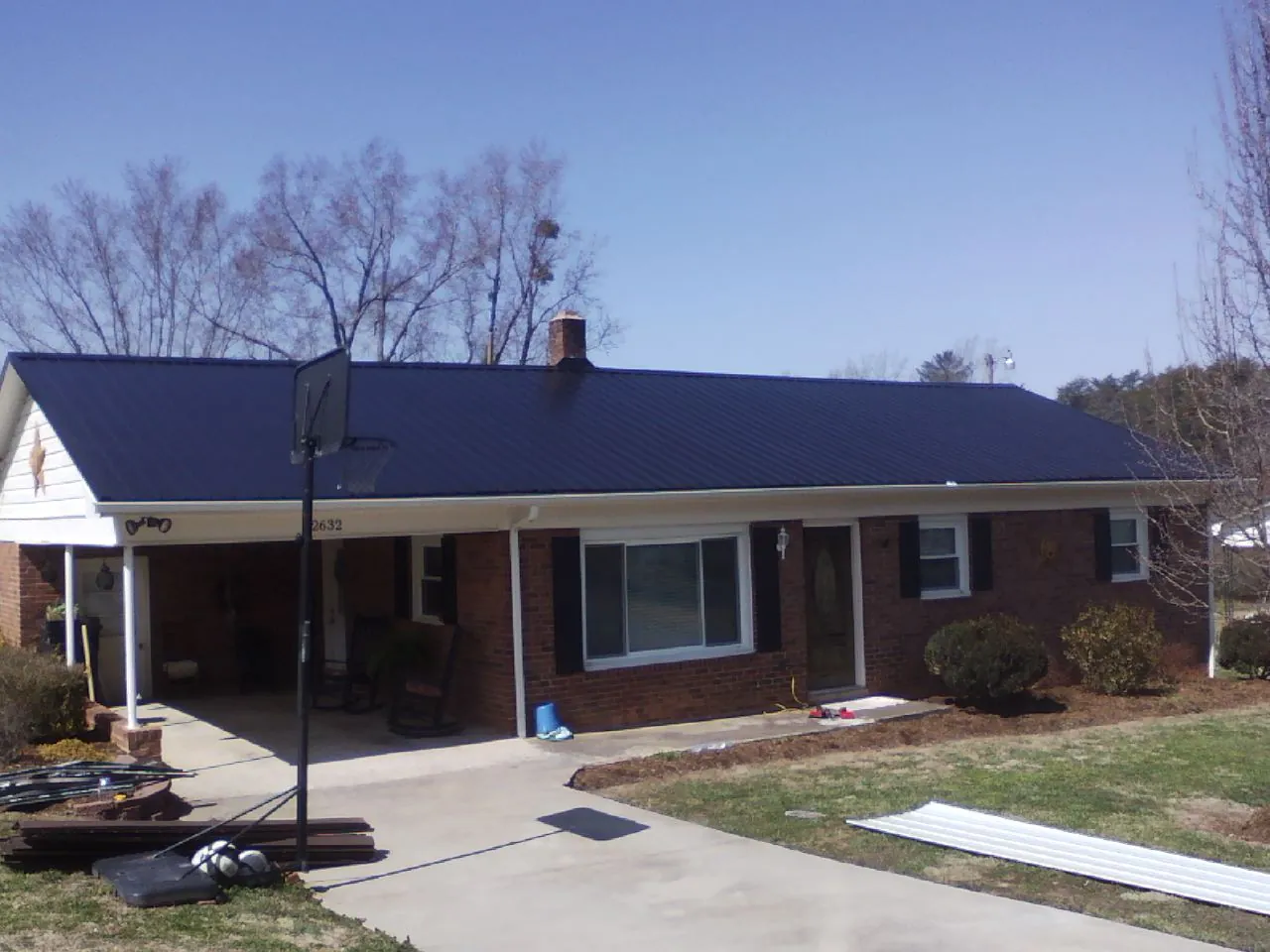 Finished dark blue metal roof on a brick ranch with a carport in Smithfield